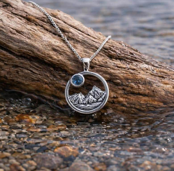 Round mountain scene pendant with blue Montana sapphire 