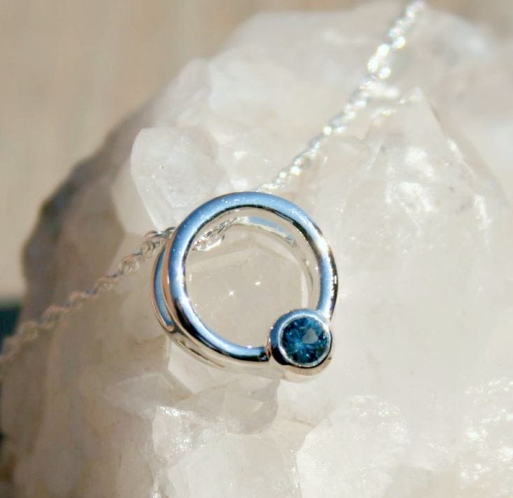 Silver ring with a blue gemstone on a white stone background