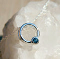 Silver ring with a blue gemstone on a white stone background