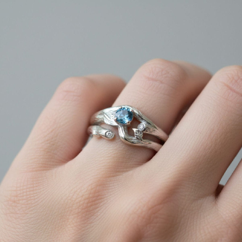 Silver ring with a blue montana sapphire on a hand against a gray background