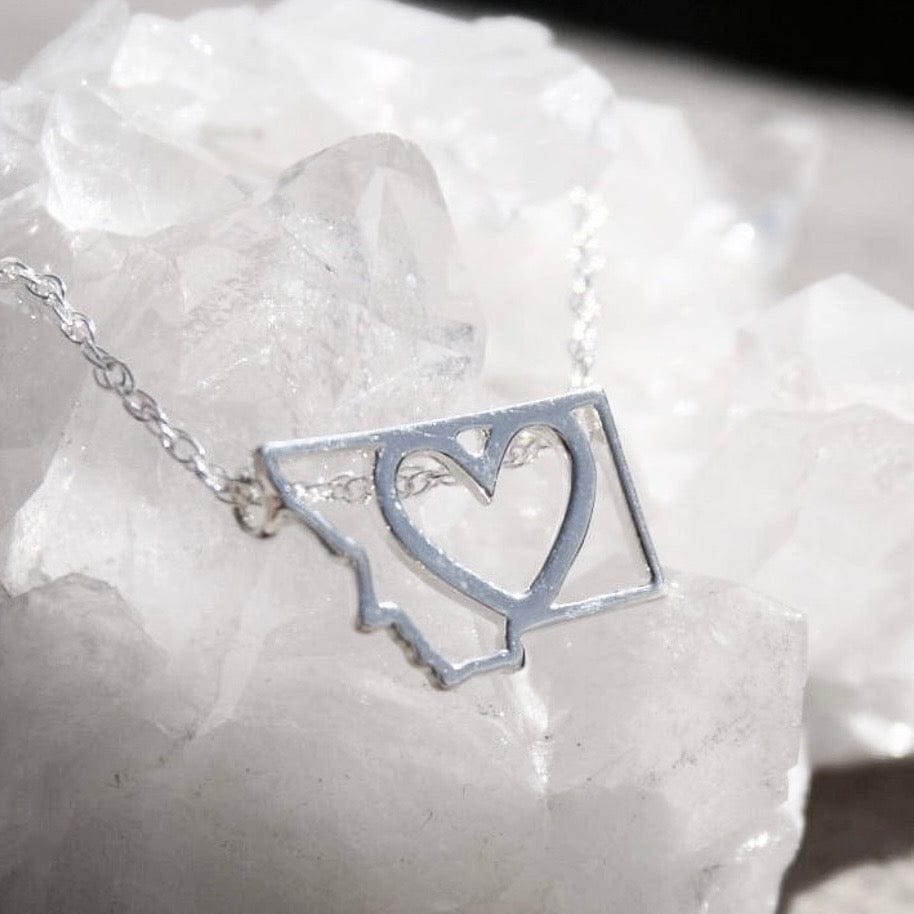Silver necklace with a heart-shaped pendant on a white stone background